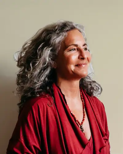 Heidi Feinstein in a red wrap top, smiling, looking to the side