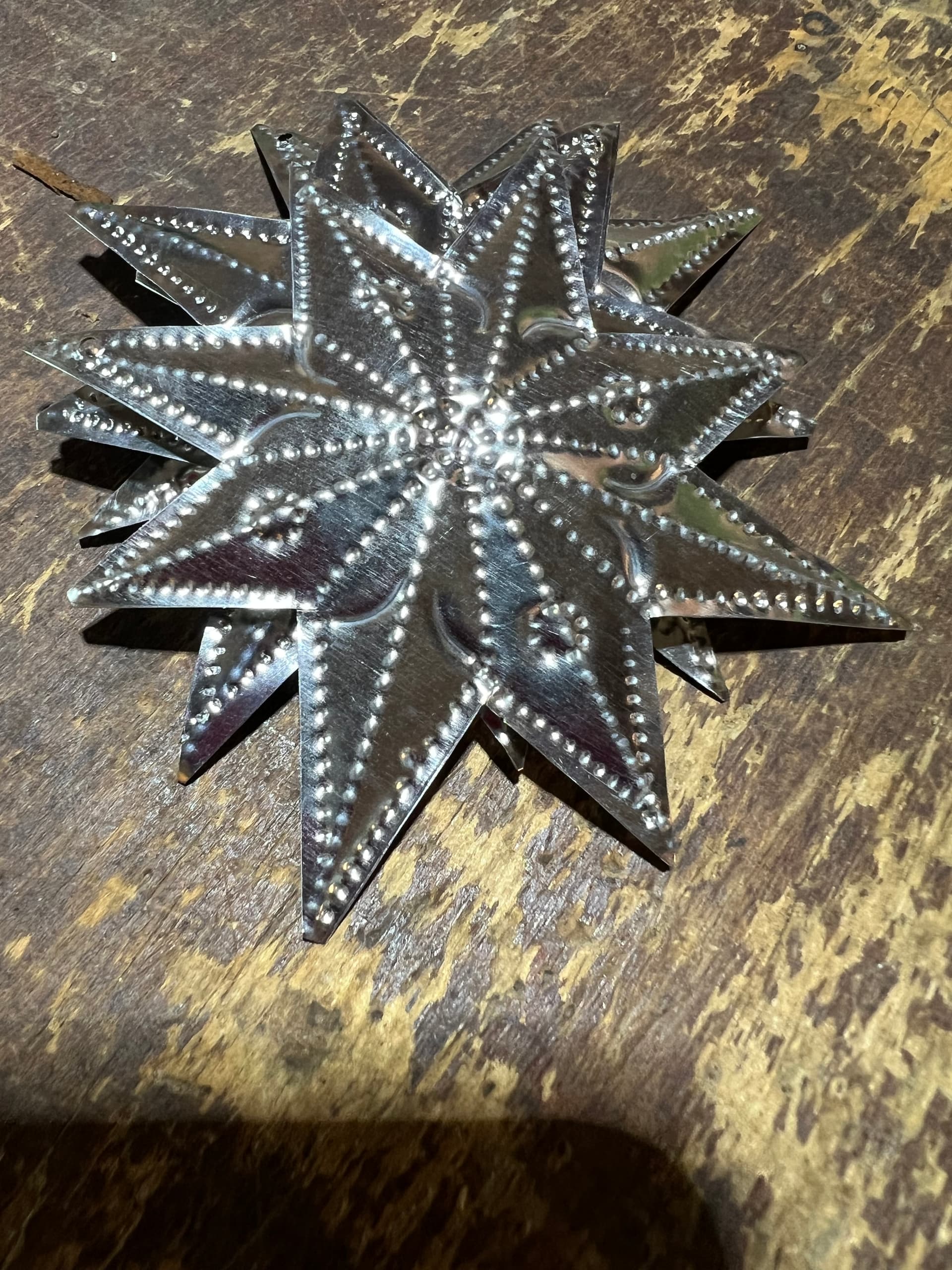 A hand-punched tin star on weathered wood, made from recycled tin
